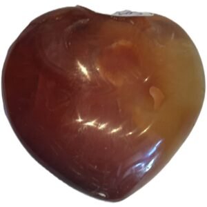 Carnelian heart 97 2 sians emporium Smooth polished carnelian carved heart palm stone with translucent amber red tones and natural circular orbicular inclusions isolated on a white background